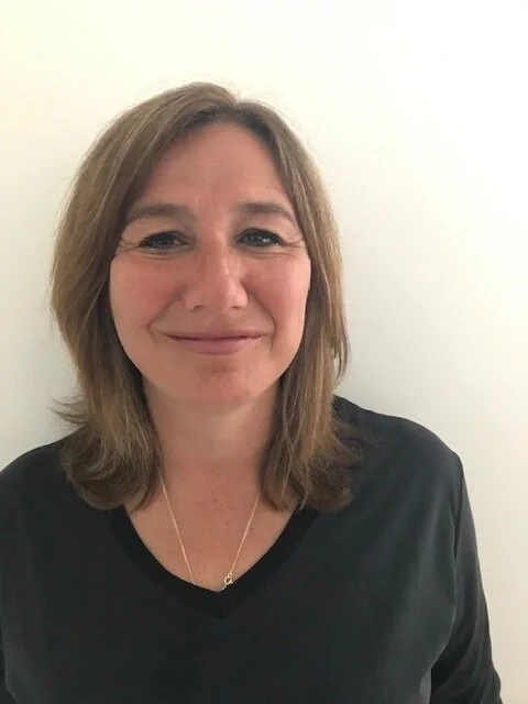 Portrait of a smiling Lisa against a neutral background.