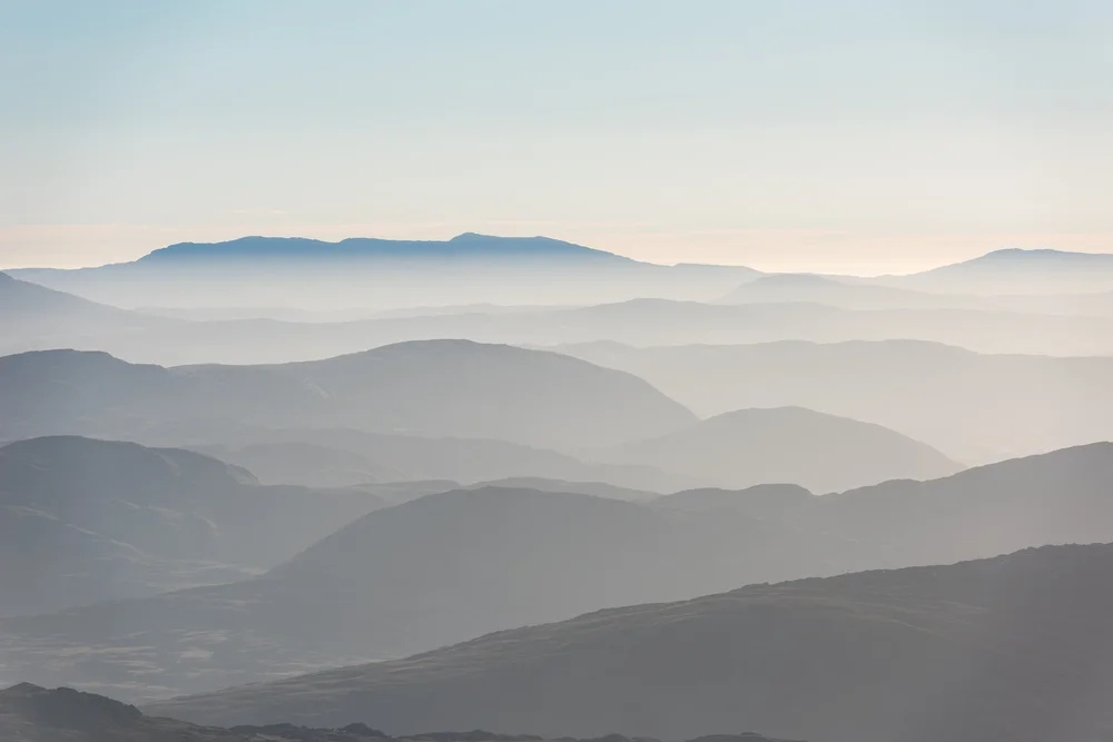 Layers of misty mountains under a pale sky