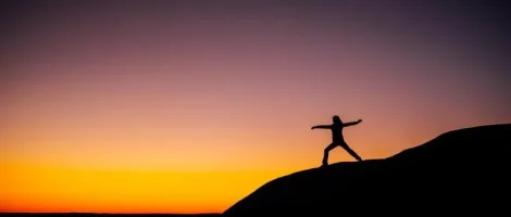 Silhouette of a person stretching at sunset.